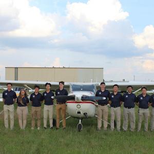 在简斯维尔举行的全国校际飞行协会(NIFA)比赛中，菠菜网lol正规平台精密飞行队的17名成员站在一架飞机前, 威斯康辛州.